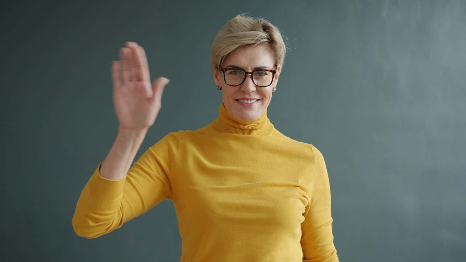 Donna sorridente che saluta con la mano