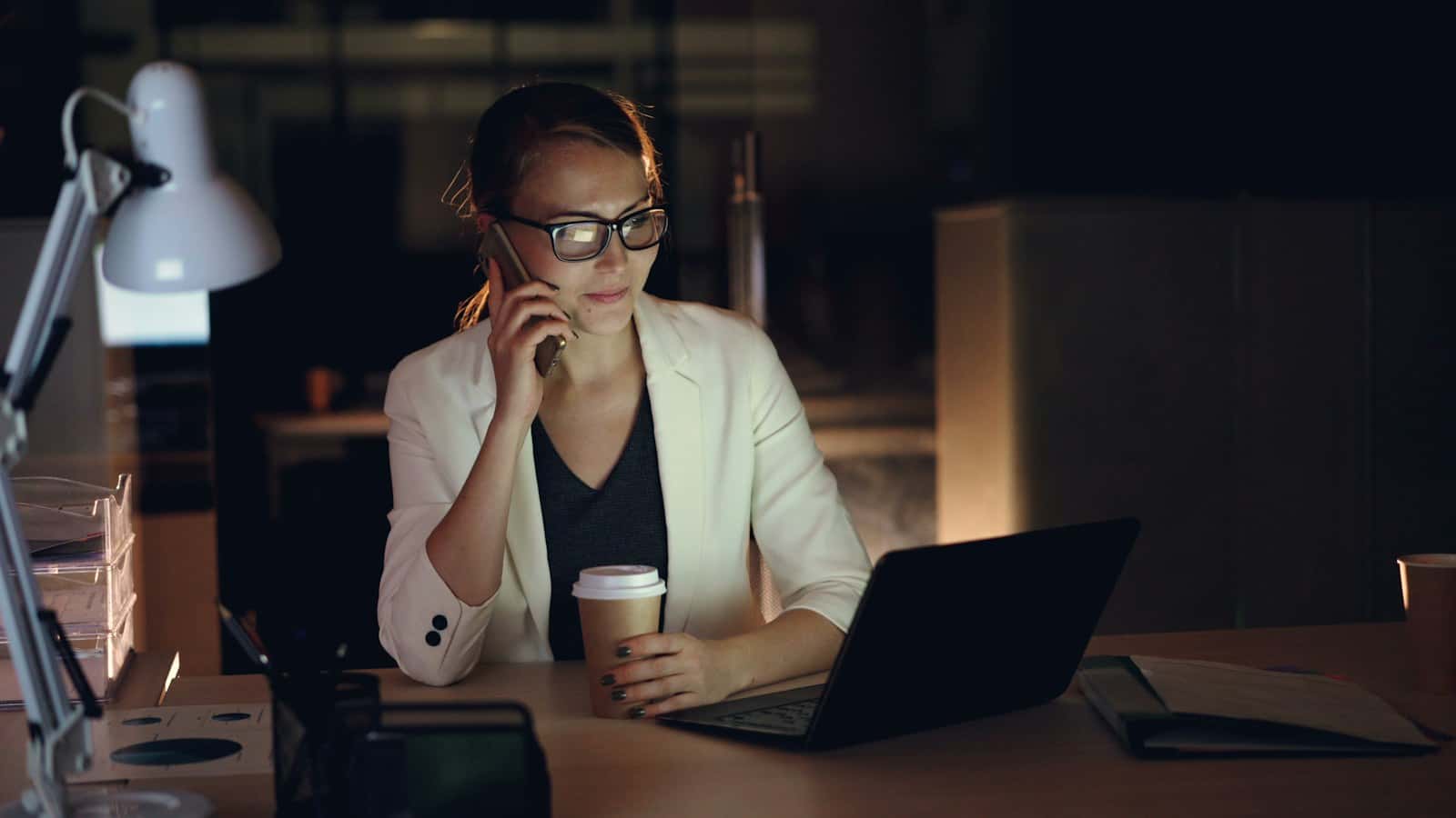 Imprenditrice al telefono, di sera, davanti al portatile